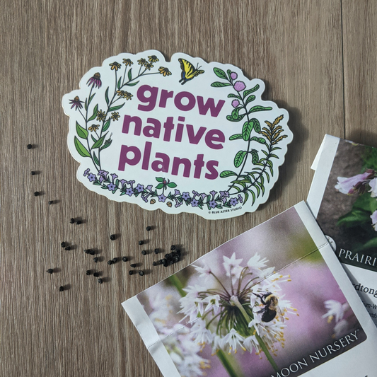 A grow native plants sticker sitting among Prairie Moon Nursery seed packets. Some nodding onion seeds are scattered on the table top.