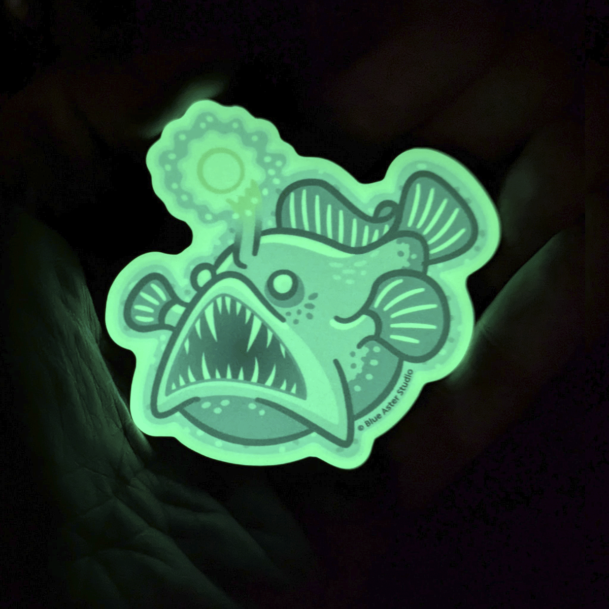 The angler fish sticker glowing bright green in the darkness