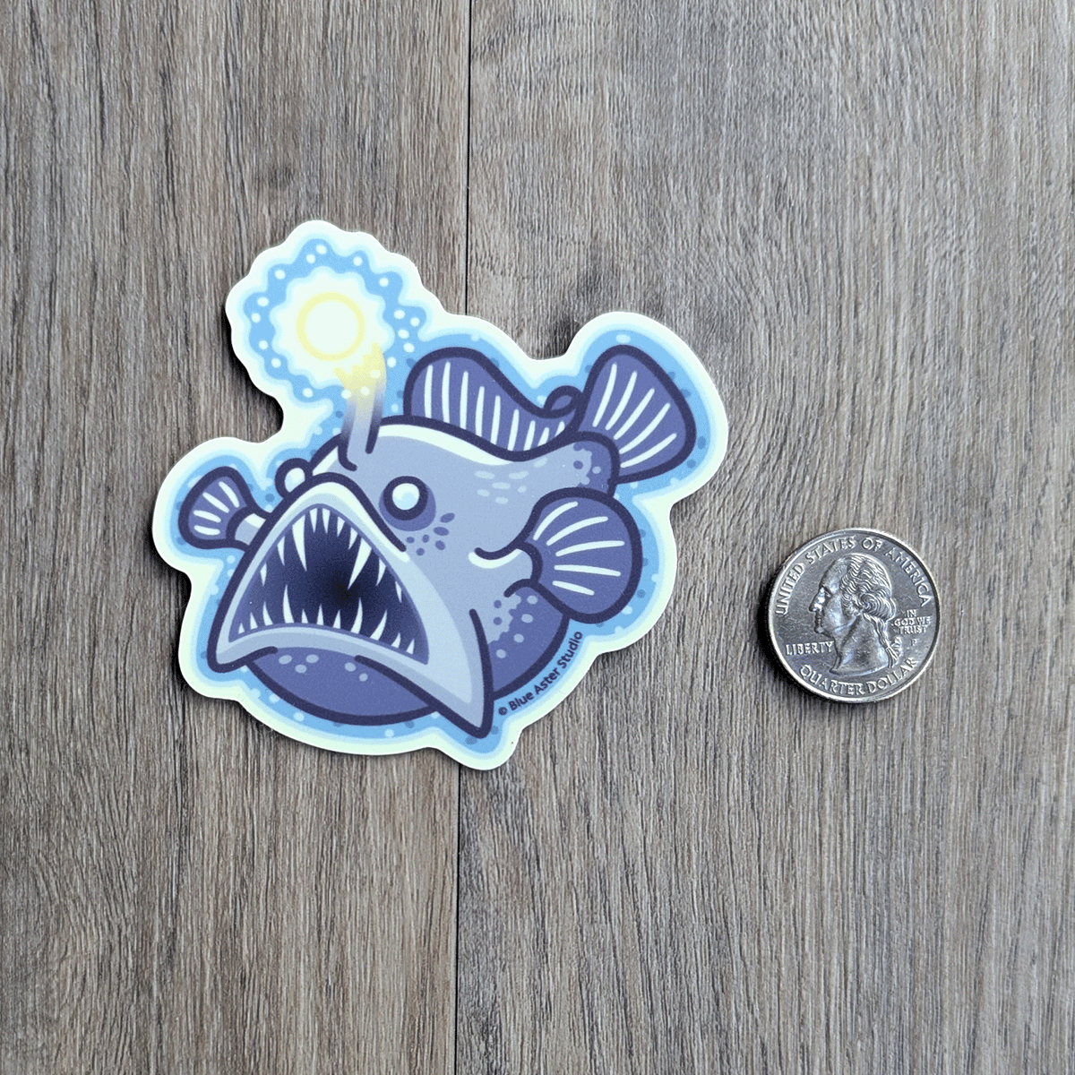 The angler fish sticker beside a USD quarter coin to demonstrate scale