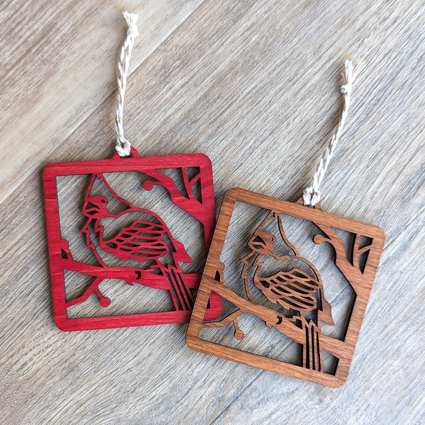 A red and a brown wooden laser cut ornament of a northern cardinal perched on a branch.