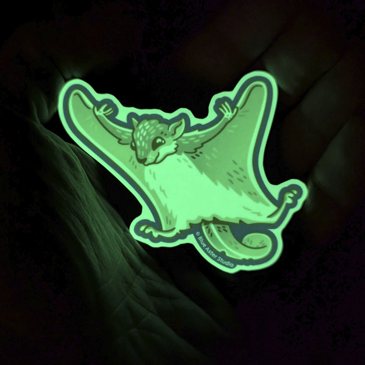 The flying squirrel sticker glowing bright green in the darkness.