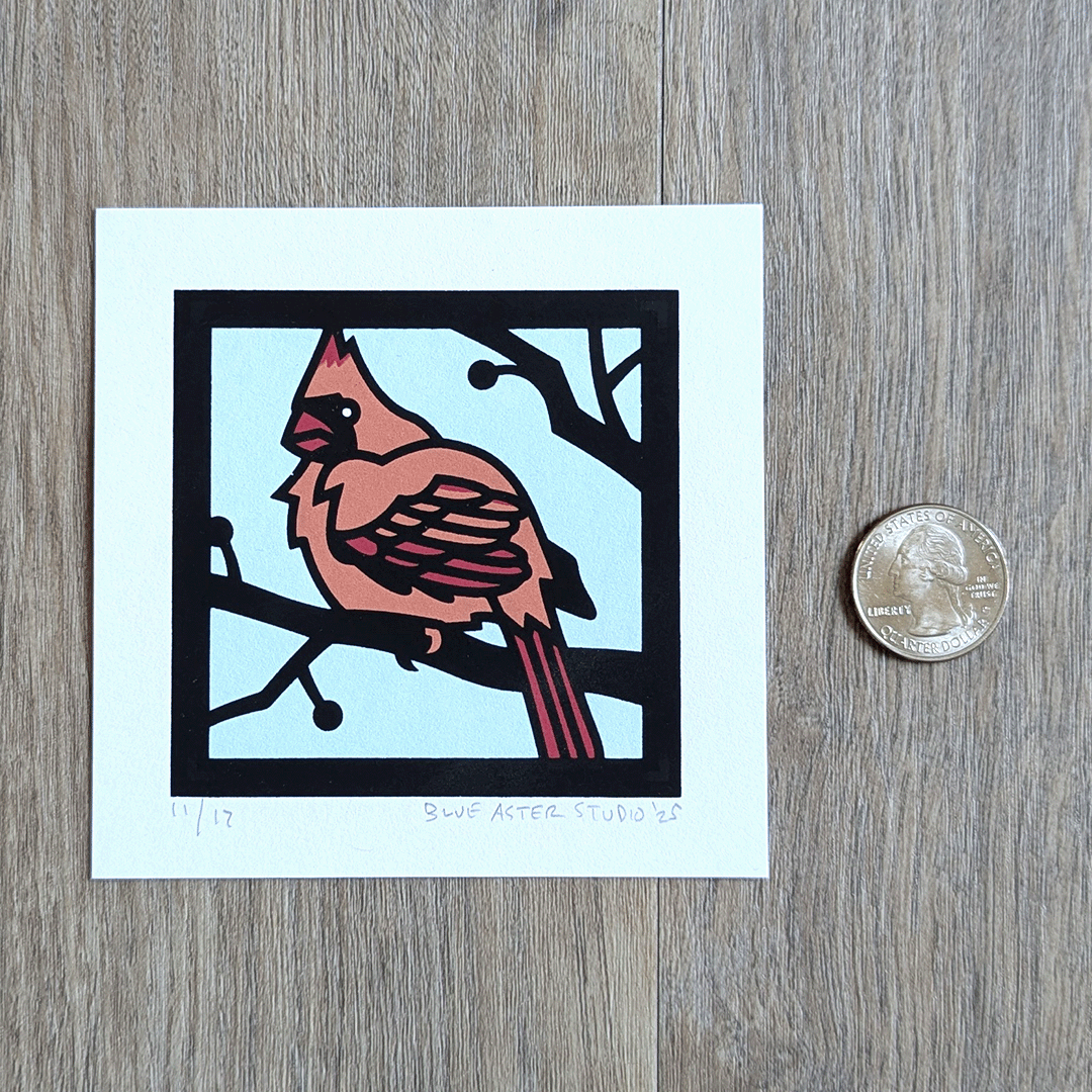 A mini screen print of a cardinal sitting next to a quarter for scale.