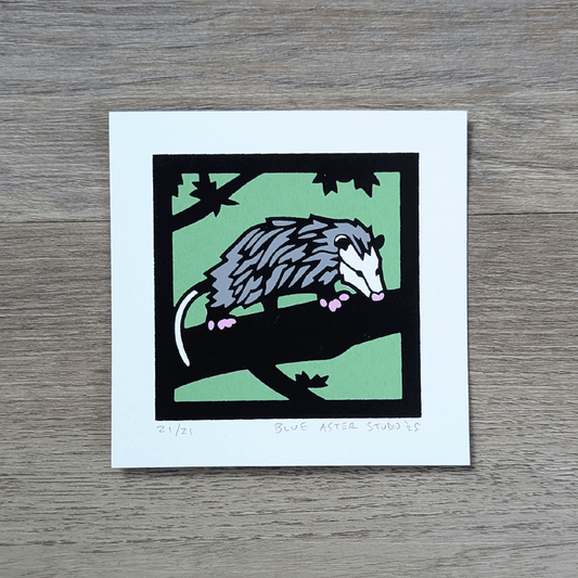 A four inch square screen printed illustration of an adult opossum walking across a tree limb.