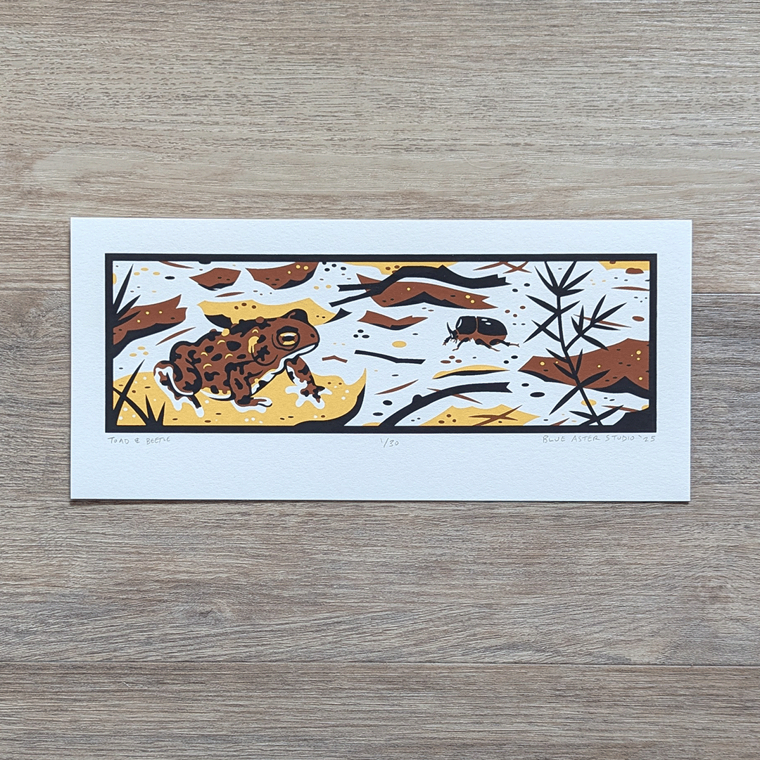 A screen printed illustration of an american toad sitting on a fallen leaf, surrounded by forest litter and a black rhinoceros beetle.