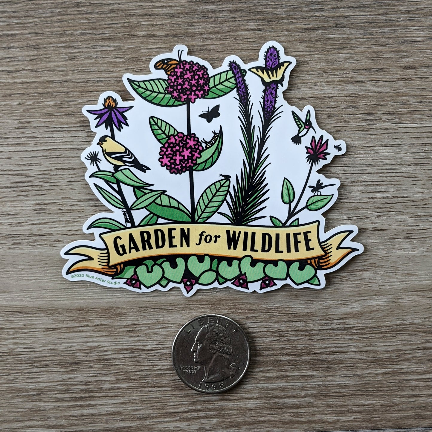 The Garden For Wildlife vinyl sticker sitting next to a USD quarter to show scale.