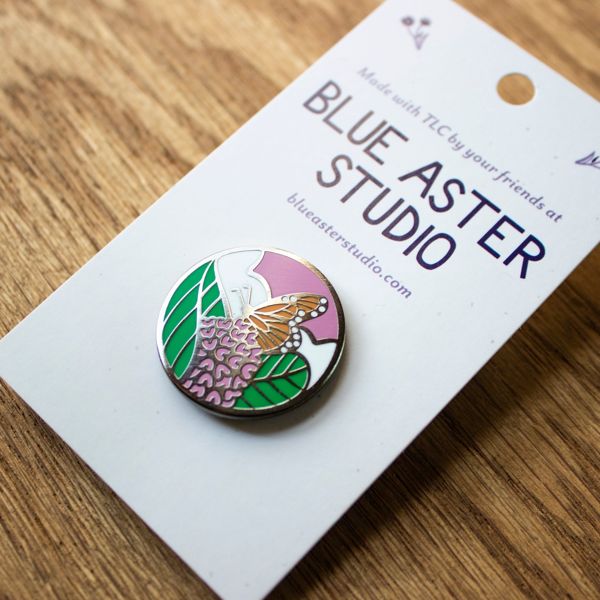 Monarch enamel pin shown at an angle with metal outlines reflecting the sun.