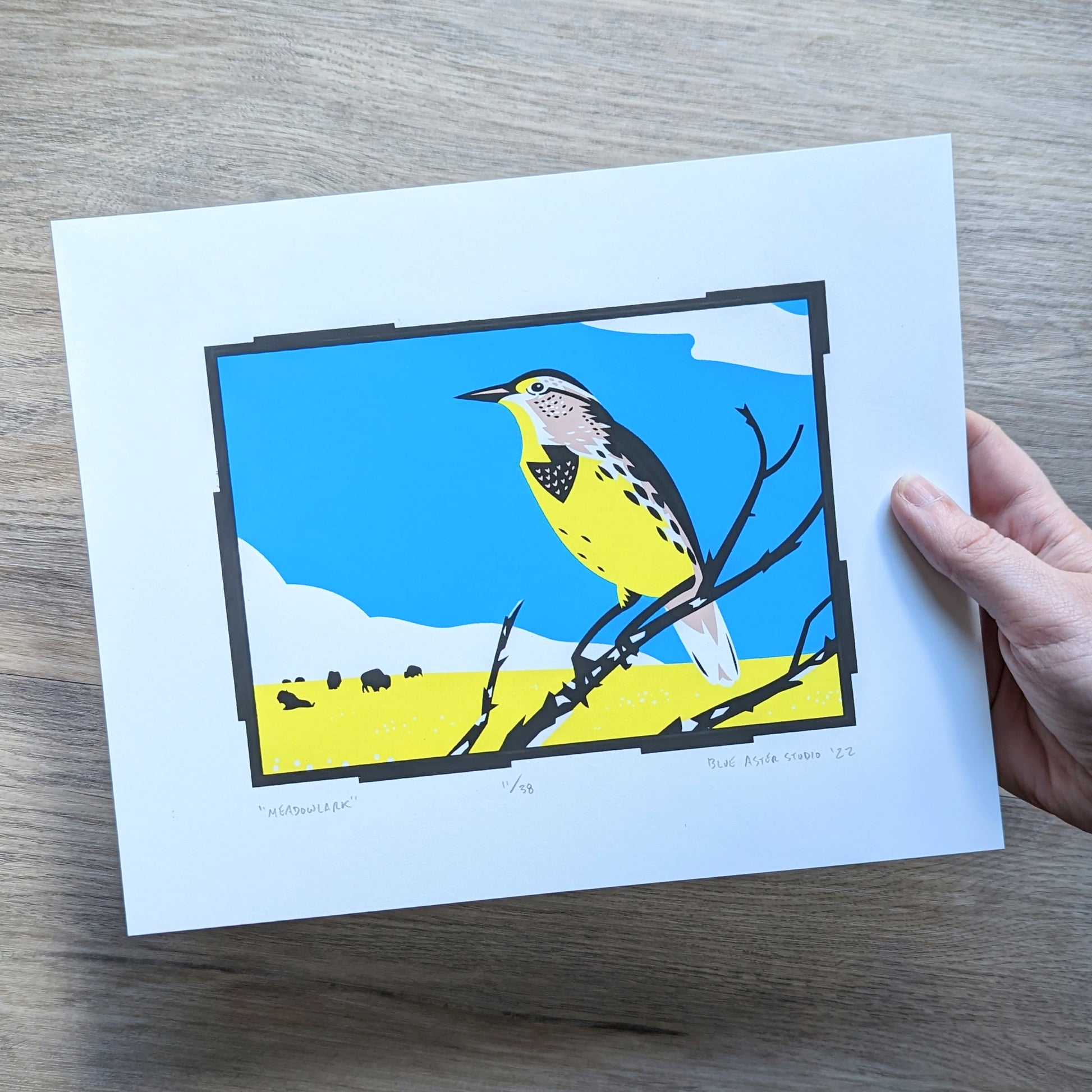 A hand holding the meadowlark screen print to show scale.