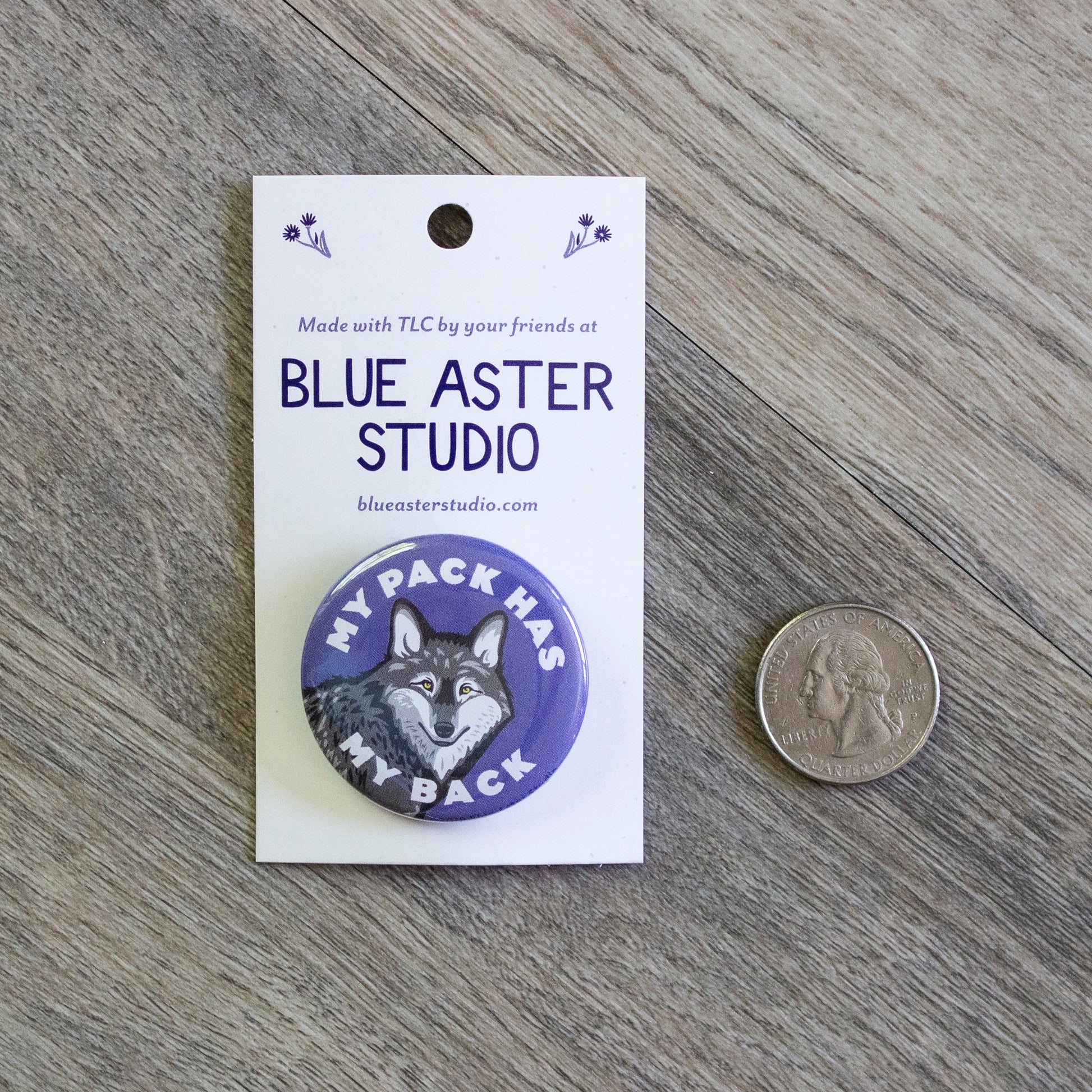 The My Pack Has My Back wolf pinback button sitting next to a USD quarter for scale.