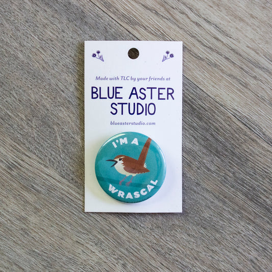 A 1.5 inch pinback button with an illustration of a wren and the words "I'm A Wrascal"