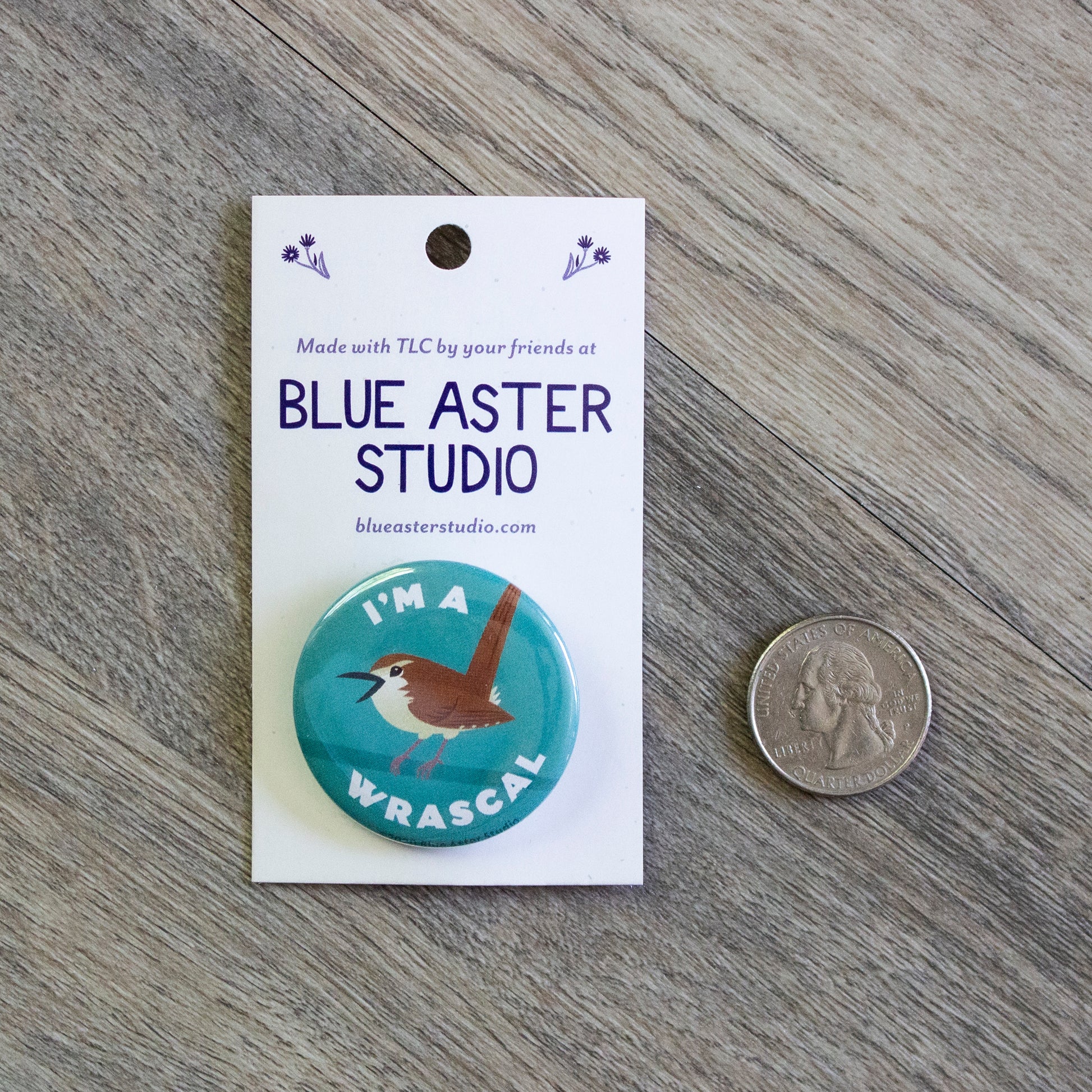 The wren button sitting next to a USD quarter to show scale.
