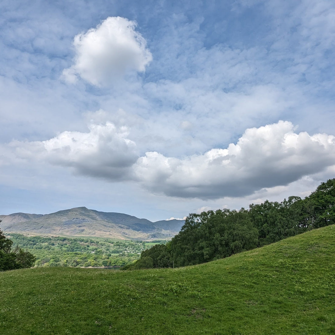 A beautiful blue sky with dramatic clouds and hills on the horizon.