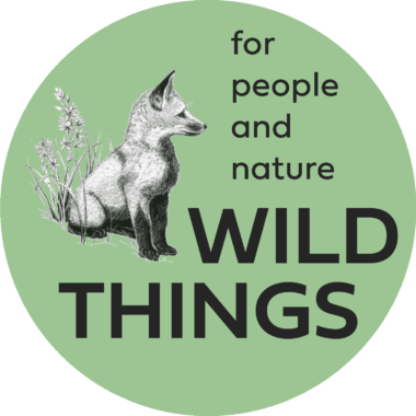 The logo for the Wild Things Community Chicago. It is a green circle with an illustration of a fox sitting and looking to the right where ther are the words "for people and nature WILD THINGS"