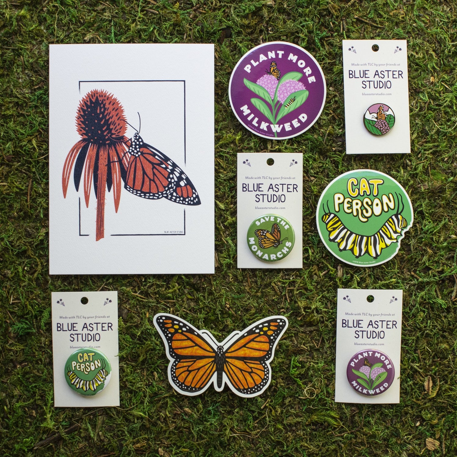 Monarch butterfly prints, stickers, buttons and enamel pins. The stickers include a monarch butterfly, monarch caterpillar, and a "Plant More Milkweed." The buttons include a "Save The Monarchs," "Plant More Milkweed," and a monarch caterpillar. 