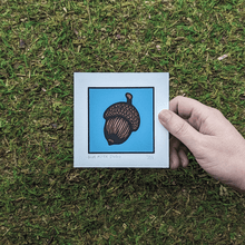 Load image into Gallery viewer, A hand holding the acorn screen print to show scale.