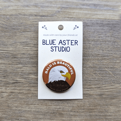 A round pinback button with an illustrated bald eagle and the text Bald is Beautiful