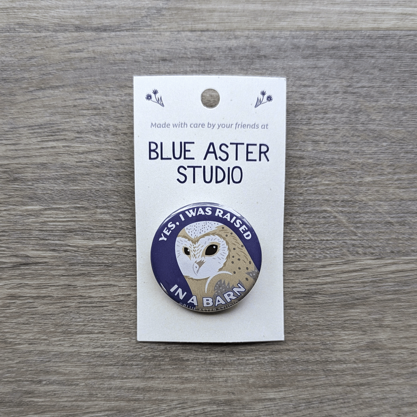 A 1.5 inch pinback button featuring an illustration of a barn owl and the words "Yes, I was raised in a barn"