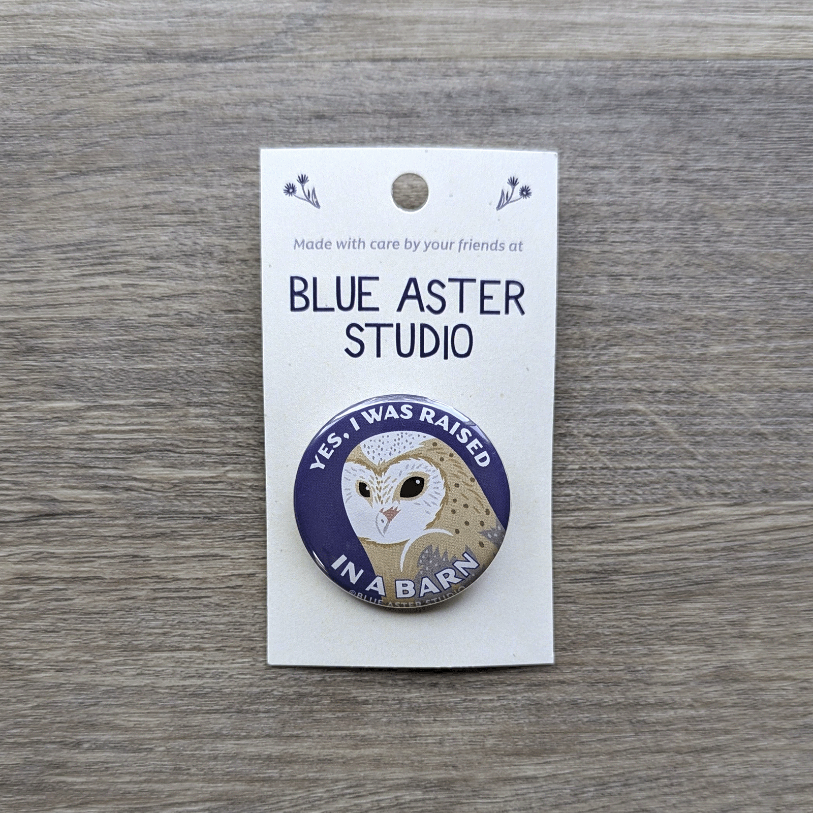 A 1.5 inch pinback button featuring an illustration of a barn owl and the words "Yes, I was raised in a barn"