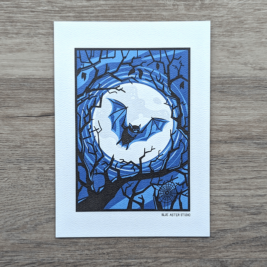 An art print of an illustration of a bat flying in front of a full moon surrouned by the silhouettes of tree branches.