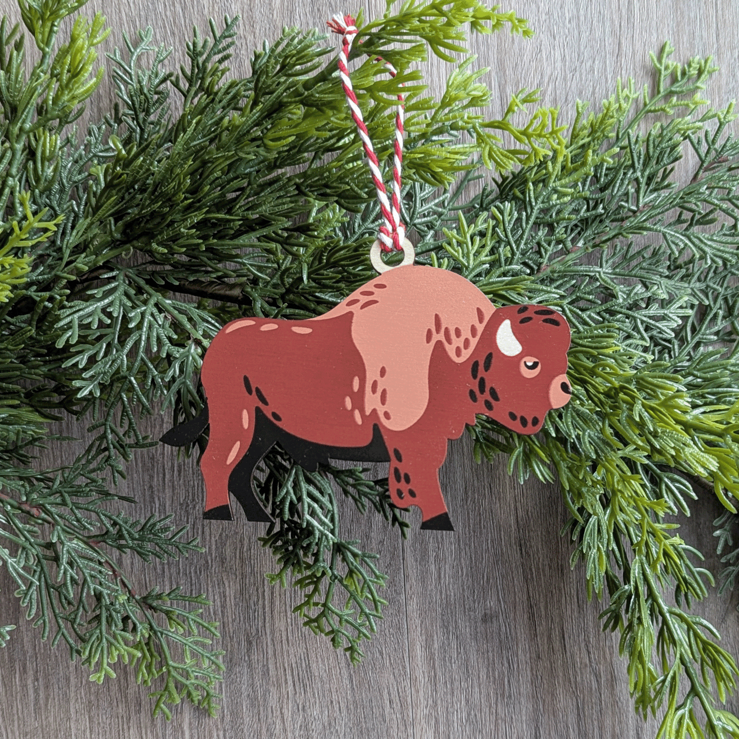 A wooden screen printed ornament of a bison hanging on a garland.