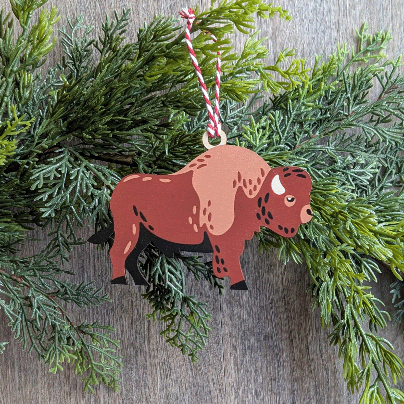A wooden screen printed ornament of a bison hanging on a garland.