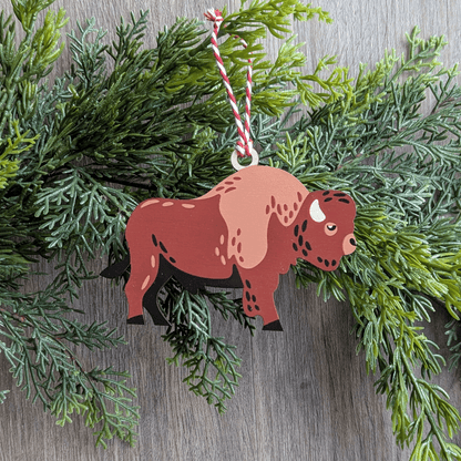 A wooden screen printed ornament of a bison hanging on a garland.