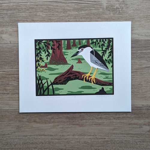 A screen print of an illustration of a black crowned night heron perched on a log in a wetland.