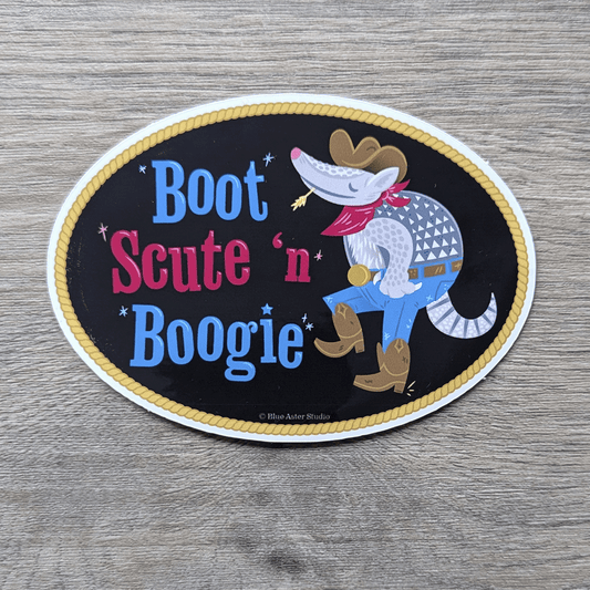 An oval-shaped sticker featuring an illustration of a cartoony armadillo in jeans, boots, cowboy hat, and bandana dancing. Next to it is the text Boot Scute and Boogie.