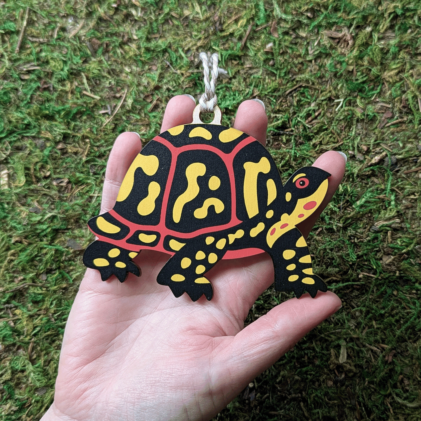 A wooden screen printed ornament of a box turtle held in hand; it is about the size of the palm of the hand.