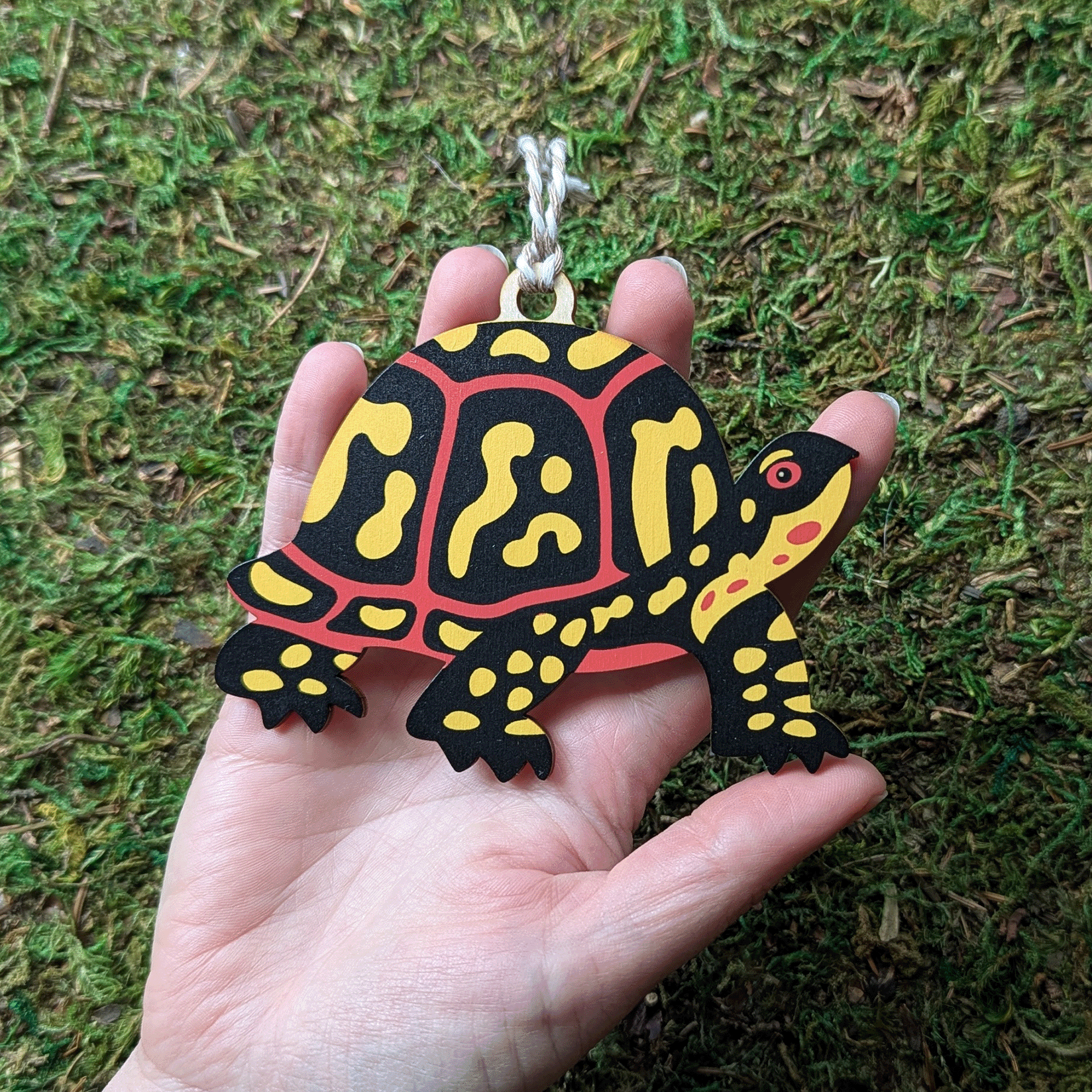 A wooden screen printed ornament of a box turtle held in hand; it is about the size of the palm of the hand.