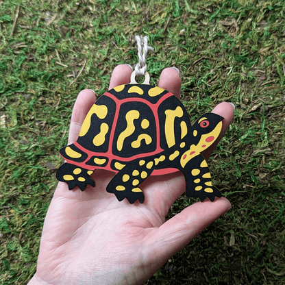 A wooden screen printed ornament of a box turtle held in hand; it is about the size of the palm of the hand.