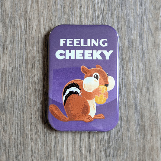 A two inch by three inch rectangular magnet featuring an illustrated chipmunk holding a peanut, set against a purple background. The text above the chipmunk reads "Feeling Cheeky."