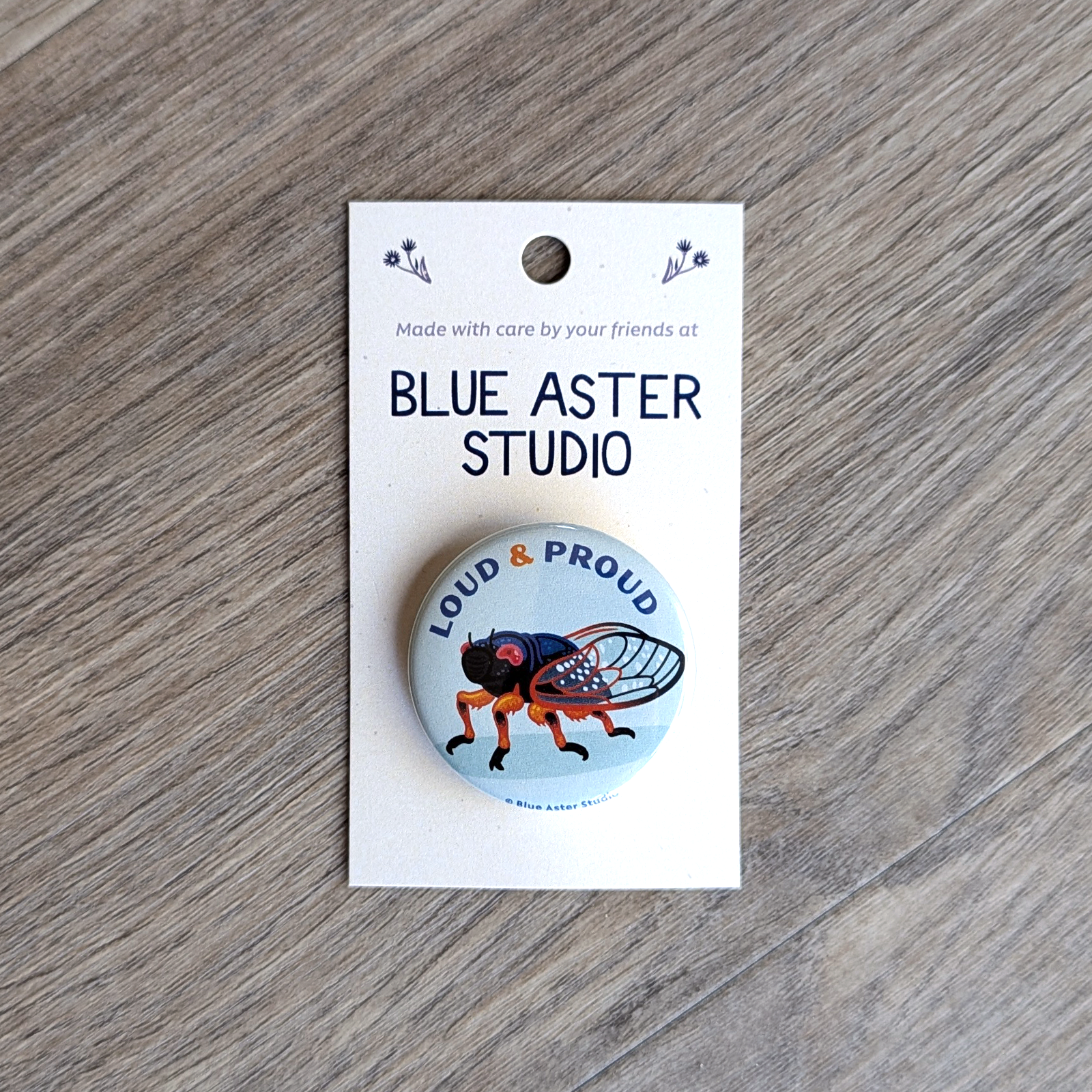 1.5 inch button of a cicada with the text Loud and Proud.