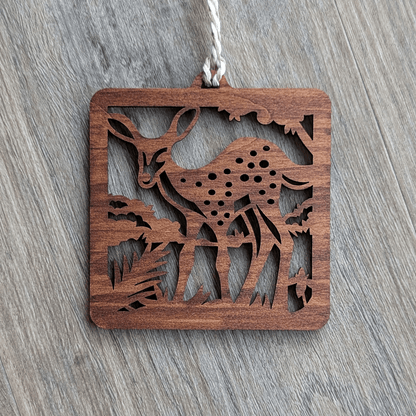 A square brown wooden ornament of a spotted fawn.