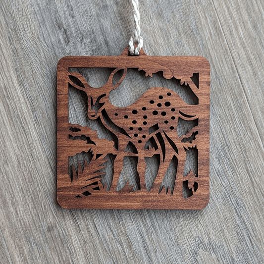 A square brown wooden ornament of a spotted fawn.