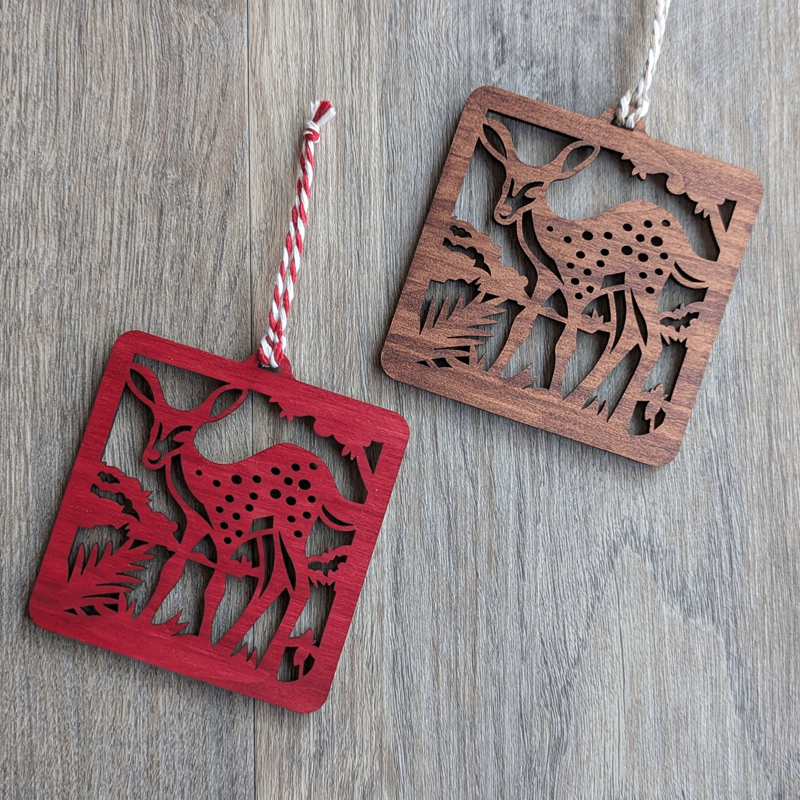 Two square wooden ornaments of a spotted fawn in brown and red stains.