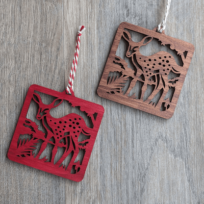 Two square wooden ornaments of a spotted fawn in brown and red stains.