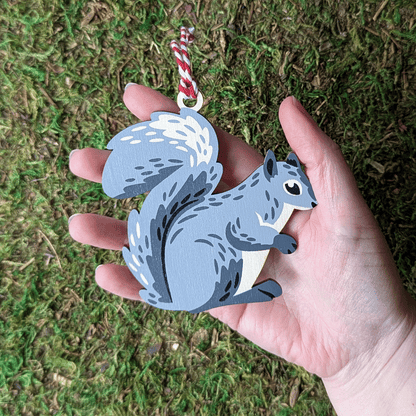 A wooden screen printed ornament of a squirrel held in hand, about the size of the palm.