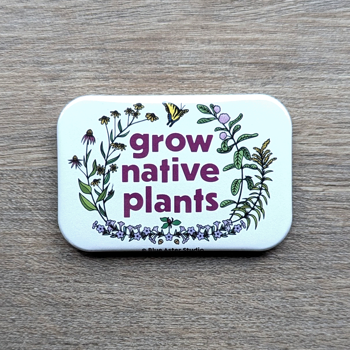 A 2 inch by 3 inch refrigerator magnet which features illustrations of native plants of the Eastern United States (milkweed, goldenrod, wild petunia, brown eyed susan, purple coneflower) with the words grow native plants in the center of them.