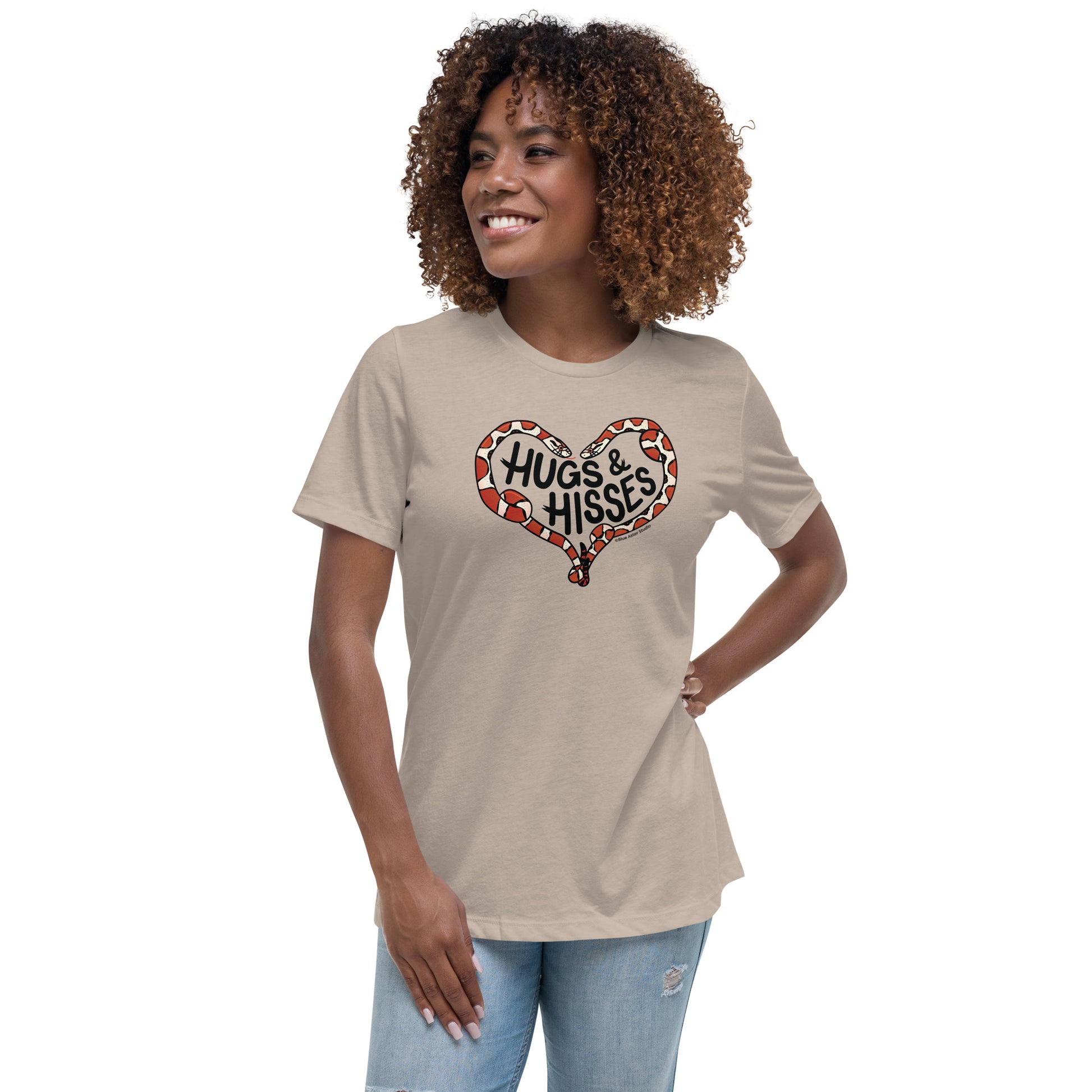 A woman wearing a tan t-shirt with a pair of illustrated corn snakes forming a heart around the text "Hugs and Hisses"
