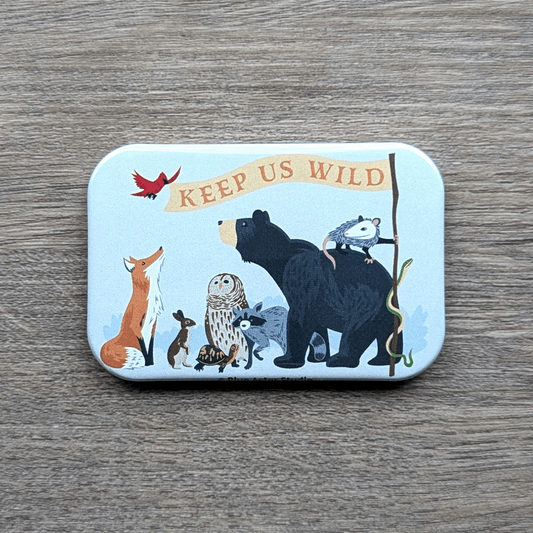 A magnet that features illustrations of a bear, opossum, snake, raccoon, rabbit, owl, turtle, fox, and northern cardinal holding a "Keep Us Wild" flag.