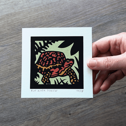 The 4x4 mini box turtle screen print being held in a hand.