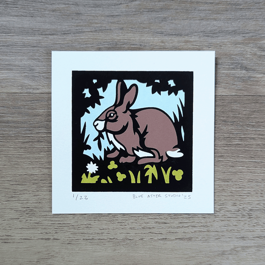 A four inch square screen printed illustration of a eastern cottontail rabbit eating foliage
