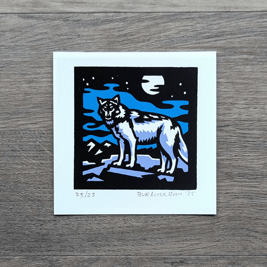 A square screen printed artwork of a gray wolf standing on a flat rock with mountains in the distance. A full moon shines above.