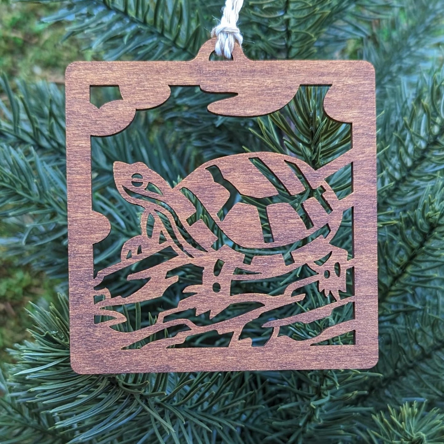 The brown turtle ornament hung on an evergreen tree.