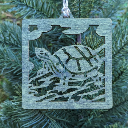 The green turtle ornament hung on an evergreen tree.