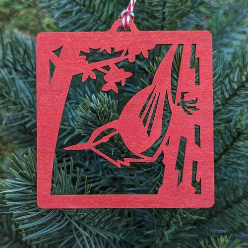 The red nuthatch ornament hung on an evergreen tree.