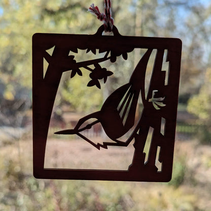 The red nuthatch ornament in silhouette in front of a window.