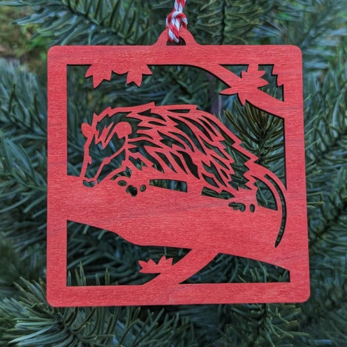 The red opossum ornament hung on an evergreen tree.