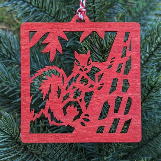 The red squirrel ornament hung on an evergreen tree.