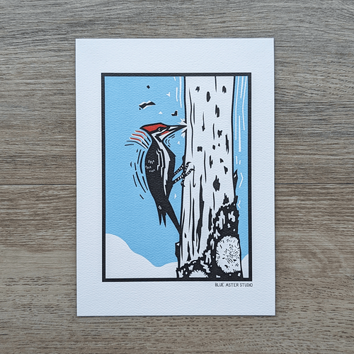 A 5x7 art print of a pileated woodpecker perched on a tree pecking at the bark.